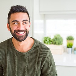 Man in a green shirt standing in kitchen and smiling